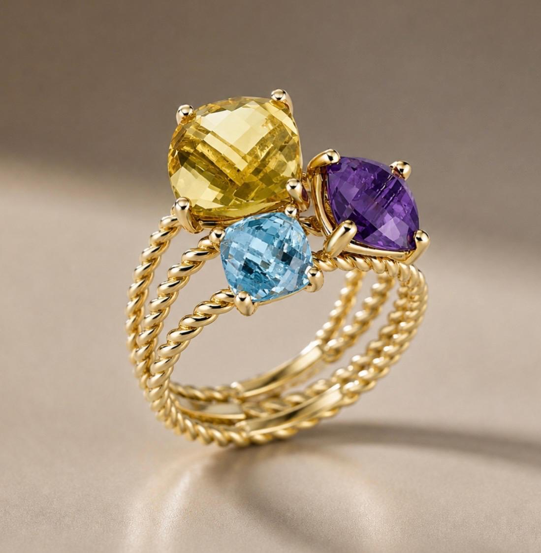 Anello “Tre pietre” in oro giallo 18k (g. 6,30). Pietre: quarzo citrico, ametista, topazio azzurro (g. 1,50) per un totale di g. 7,80.